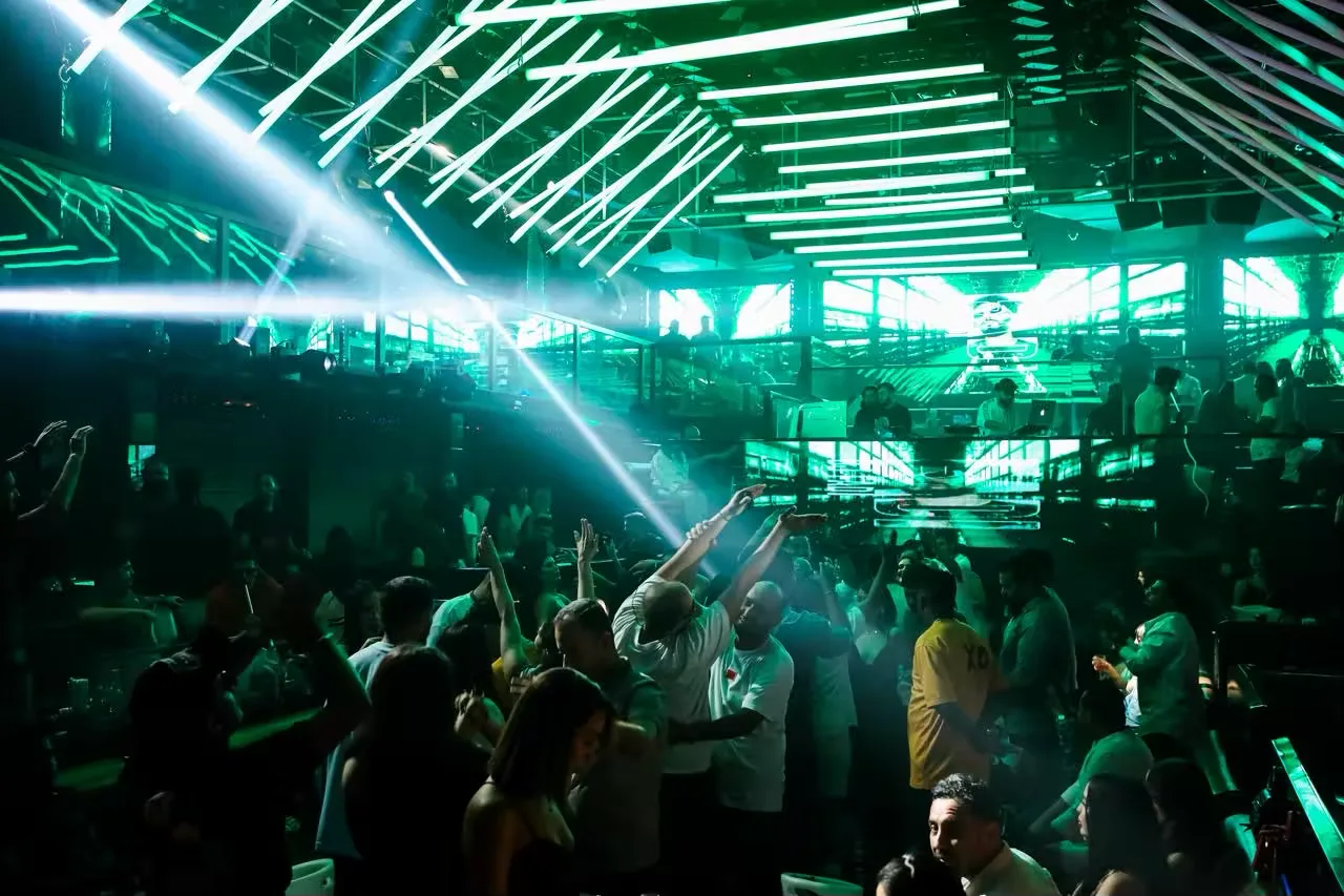 XO Club Dubai crowd beneath green laser lighting and ceiling light bars